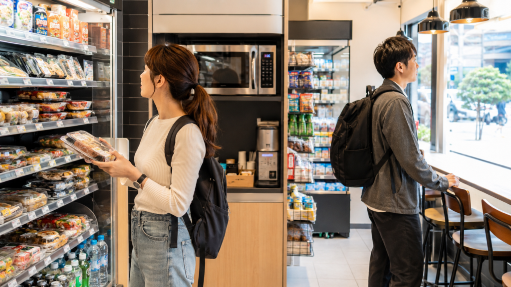 韓国コンビニで弁当を選びながら温め方や食べ方を確認する日本人旅行者の様子